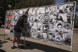 (A volunteer sets up an art installation displaying names and faces of people who have been detained, deported, or sent to offshore camps during ICE raids in Southern California, at Olvera Street Plaza in Los Angeles, on Thursday, July 3, 2025. (AP Photo/Damian Dovarganes)