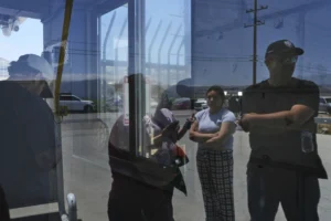 People wait outside of Glass House Farms, a day after an immigration raid on the facility, Friday, July 11, 2025, in Camarillo, Calif. (AP Photo/Jae C. Hong)
