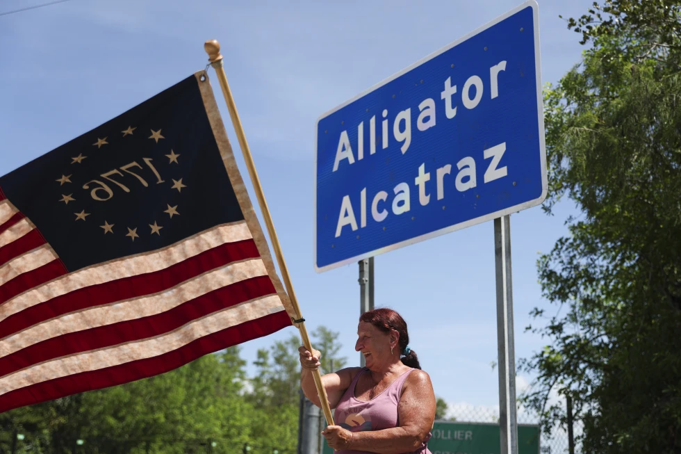 Rana Mourer waves an American flag outside of the migrant detention facility dubbed “Alligator Alcatraz,” at the Dade-Collier Training and Transition facility, Saturday, July 12, 2025 in Ochopee, Fla. (AP Photo/Alexandra Rodriguez)