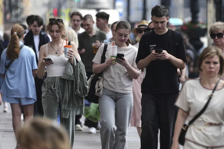 (Pedestrians look at their phones while walking through St. Petersburg, Russia, on Monday, July 14, 2025. AP Photo: Dmitri Lovetsky)