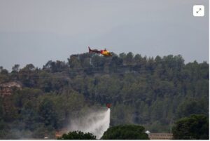 (A helicopter helps to extinguish an ongoing wildfire in Xerta, which is one of the confined villages in the Tarrragona province in Catalonia, Spain, July 8, 2025. REUTERS/Nacho Doce Purchase Licensing Rights)