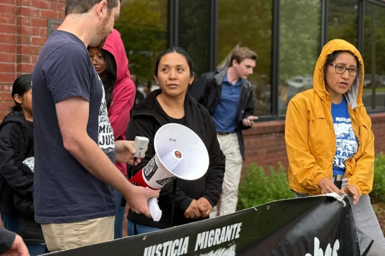(Wuendy Bernardo, foreground center, a migrant dairy farmworker at risk of deportation, is greeted by Migrant Justice staff member Will Lambek, left, outside a U.S. Immigration and Customs Enforcement office in St. Albans, Vt., on Friday, June 20, 2025. Lambek led a rally in support of Bernardo as she reported to the office for an appointment. (AP Photo: Amanda Swinhart)