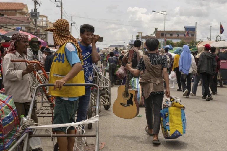 With a guitar in hand, a Cambodian migrant worker carries his belongings in Kamrieng, after crossing the Daung International Border Check Point between Cambodia and Thailand on Wednesday, Aug. 6, 2025. (AP Photo/Anton L. Delgado)