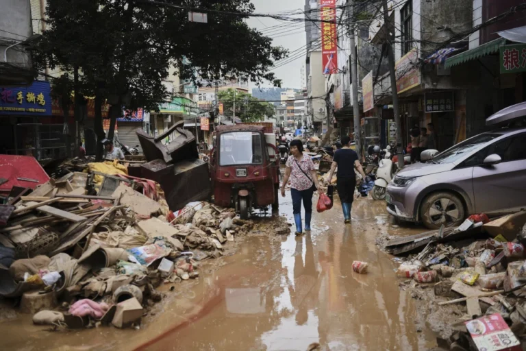 (In this photo released by Xinhua News Agency, residents wade through debris along a flood-hit street after waters from a river overwhelmed towns following days of heavy rain, in Huaiji County, south China’s Guangdong Province on June 19, 2025. (Deng Hua-Xinhua via AP, File)