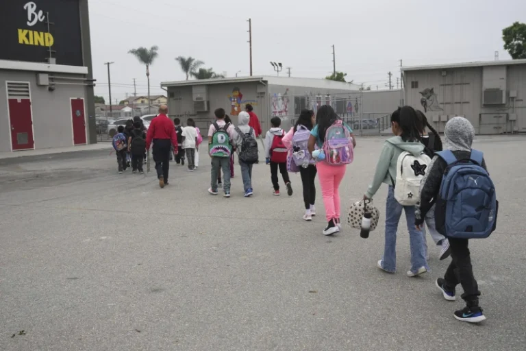 (Students and family members are escorted into school on the first day of school Thursday, Aug. 14, 2025, in Los Angeles. AP Photo: Marcio Jose Sanchez)