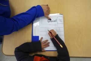 (Easterseals Head Start program teaching assistant Tania Ortiz helps a student practice writing his name, Jan. 29, 2025, in Miami.  AP Photo: Rebecca Blackwell, File)
