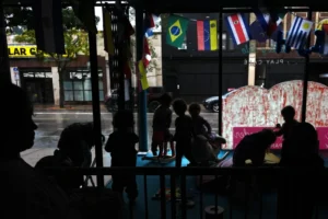 (A nanny keeps watch as children play in the window at Luna y Cielo Play Cafe, where they practice and learn Spanish through play, in Chicago’s Logan Square neighborhood, Wednesday, Oct. 15, 2025.  AP Photo: Rebecca Blackwell)