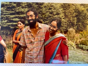 (Tejaswini Rao chats with party guests while Subramanyam and Saraswathi Vedam embrace during their parents’ wedding anniversary party at State College, Pa., in August 1981. Photo: Saraswathi Vedam via AP)
