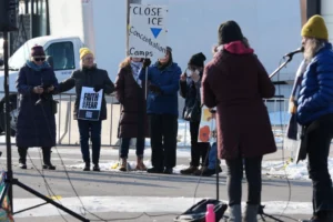 (Protesters gather as Law enforcement officers guard outside an ICE processing facility in the Chicago suburb of Broadview, Ill., Friday, Dec. 12, 2025.  AP Photo: Nam Y. Huh)