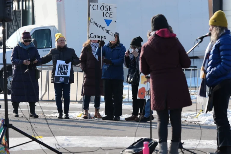 (Protesters gather as Law enforcement officers guard outside an ICE processing facility in the Chicago suburb of Broadview, Ill., Friday, Dec. 12, 2025.  AP Photo: Nam Y. Huh)