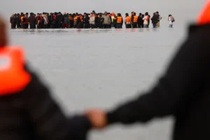 (Migrants push a small boat in an attempt to reach Britain, Thursday, Nov. 6, 2025 in Gravelines, northern France.  AP Photo: Jean-Francois Badias, file)