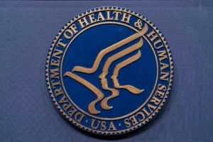 (FILE = The Health and Human Services seal is seen before the news conference of Secretary Robert F. Kennedy Jr. at the Hubert Humphrey Building Auditorium in Washington, Wednesday, April 16, 2025.  AP Photo: Jose Luis Magana, File)