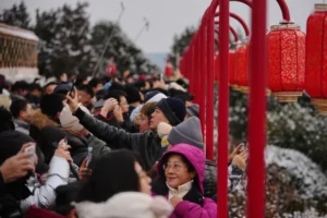 (People view the snow-covered Forbidden City from a pavilion with lantern decorations at Jingshan Park in Beijing on Sunday.  AP Photo: Andy Wong)