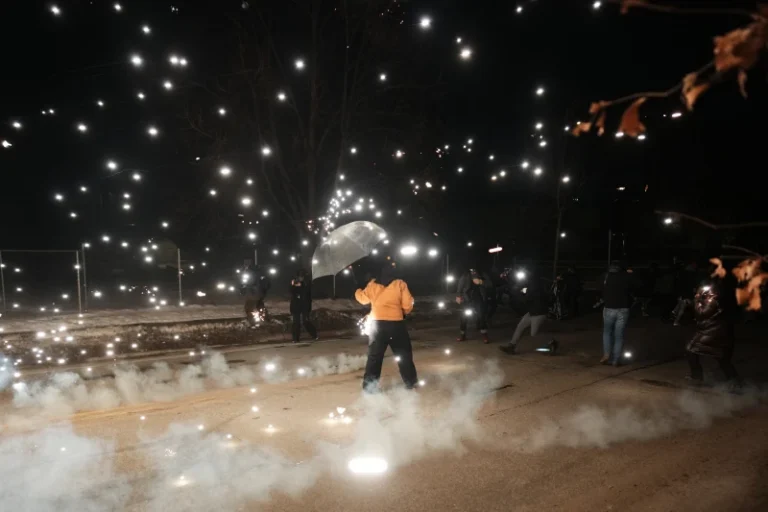 (A protester holds an umbrella as sparks fly from a flash bang deployed by law enforcement on Wednesday, Jan. 14, 2026, in Minneapolis.  AP Photo: Adam Gray)