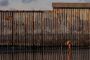 (A man takes an image with his phone next to where the border wall separating Mexico and the United States reaches the Pacific Ocean Jan. 28, 2025, in Tijuana, Mexico. AP Photo: Gregory Bull, File)