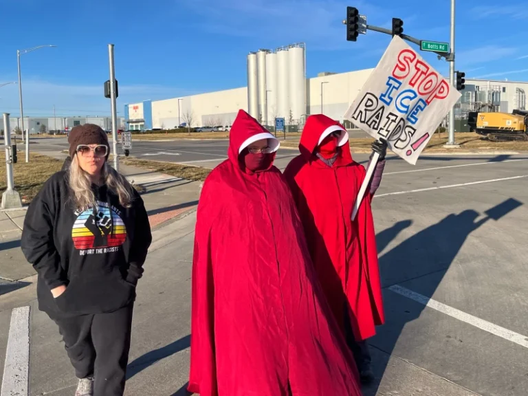 (Melissa Kane, a self-described worried mother, joins protestors clad in red cloaks inspired by the dystopian novel and TV series, “The Handmaid’s Tale,” as they protest outside a warehouse federal officials are touring to consider repurposing for an ICE detention facility, in Kansas City, Mo., Thursday, Jan. 15, 2026.  AP Photo: Heather Hollingsworth)
