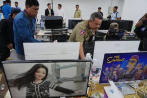 (Bun Sosekha, Deputy Commissioner in charge of Security Unit, Phnom Penh Municipal Police, checks equipment confiscated in a raid by Cambodian police at a scam center in Phnom Penh, Cambodia, Wednesday, March 11, 2026. Photo: AP)
