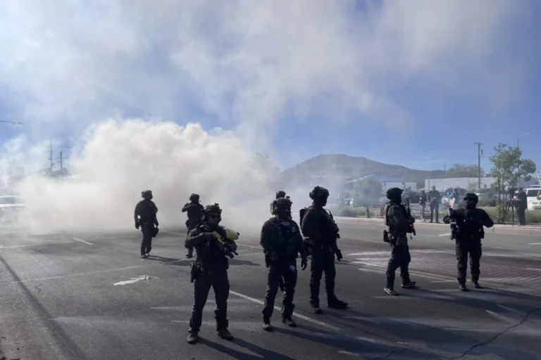 (Federal agents block Grande Avenue on Friday, Dec. 5, 2025, in Tucson, Ariz. (John Washington/Arizona Luminaria via AP)