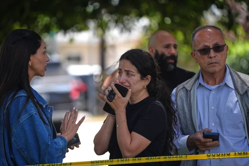 (People stand behind police tape at the scene of a shooting outside the Islamic Center of San Diego Monday, May 18, 2026, in San Diego.  AP Photo: Gregory Bull)