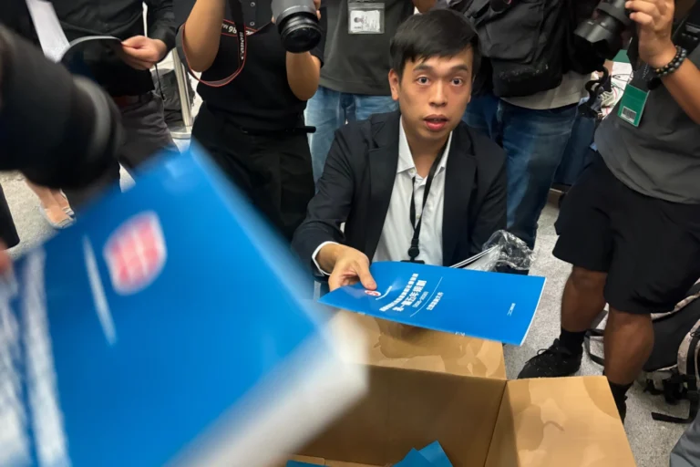 (A man gives out copies of public consultation documents for Hong Kong's first five-year plan to reporters at the government headquarters in Admiralty district of Hong Kong, Monday, June 15, 2026.  AP Photo: Kanis Leung)