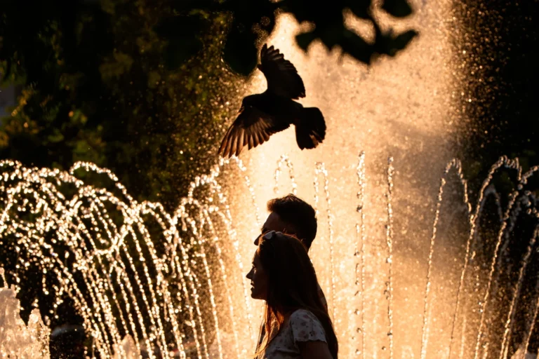 (A couple walks by a public fountain on a torrid day, as the National Weather forecaster issued an extreme heat code red warning for parts of the country, in the coming days in Bucharest, Romania, Saturday, June 27, 2026.  AP Photo: Andreea Alexandru)