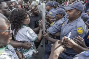 (Members of “March and March” migrant protest are confronted by members of the South African police. AFP Photo: Rajesh Jantilal)