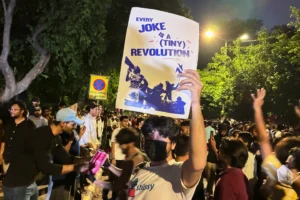(A protestor holds a placard with the message "Every Joke is a Tiny Revolution" during a demonstration demanding educational reforms as part of the Cockroach Janta Party's ongoing protest movement in New Delhi, India, Thursday, July 23, 2026.  AP Photo: Verda Sabzwari)