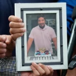 (Ronaldo Salgado and Lorenzo Jr., sons of Lorenzo Salgado Araujo, hold a photograph of their father during a news conference Wednesday, July 8, 2026, in Houston. AP Photo: David J. Phillip)