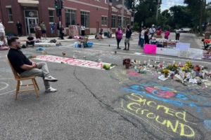 (Madison Police Shooting - Mourners gather around a memorial at the site where a man was shot and killed on Wednesday by Madison police, Thursday, July 23, 2026, in Madison, Wis.  AP Photo: Scott Bauer)