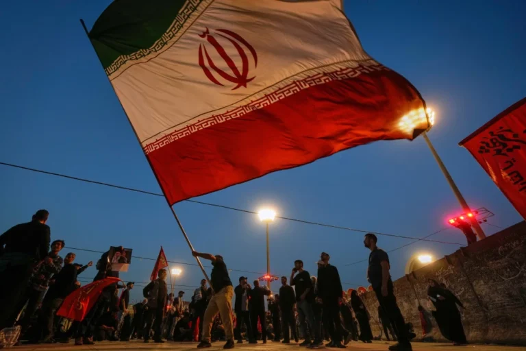 (A man waves an Iranian flag during funeral ceremonies for slain Iranian Supreme Leader Ayatollah Ali Khamenei and members of his family at Imam Khomeini Mosalla Grand Mosque in Tehran, Iran, Sunday, July 5, 2026.  AP Photo: Altaf Qadri)