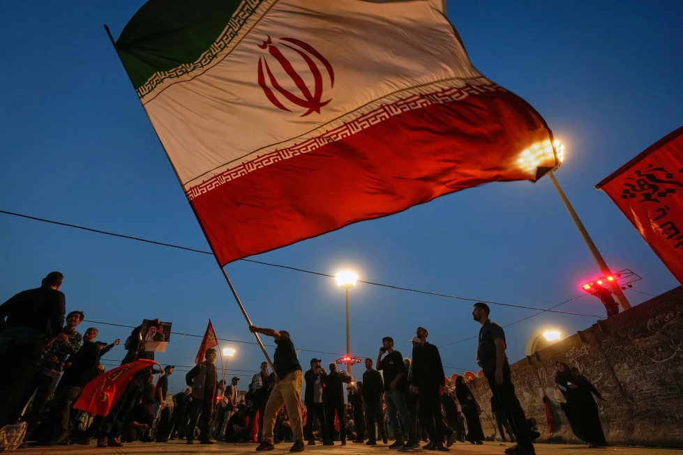 (A man waves an Iranian flag during funeral ceremonies for slain Iranian Supreme Leader Ayatollah Ali Khamenei and members of his family at Imam Khomeini Mosalla Grand Mosque in Tehran, Iran, Sunday, July 5, 2026.  AP Photo: Altaf Qadri)