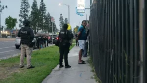 (Mukeshkumar Ahir stands handcuffed outside Stadium Inn & Spas after it was raided. Photo: DHS)