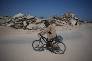 (A Palestinian man rides his bicycle by the rubble of buildings that were destroyed during the Israel Hamas war, in Khan Younis, southern Gaza Strip, Friday, July 31, 2026. AP Photo: Abdel Kareem Hana)