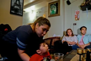 (Rosa, second from right, who wants her last name withheld, an undocumented immigrant who used to get about $190 per month from the Supplemental Nutrition Assistance Program, or SNAP, and who stopped taking benefits fearing deportation, is surrounded by her son Edgar, far right, daughter Olga, far left, and grandson Logan at their home during an interview in New York, May 17, 2017. (AP File Photo: Bebeto Matthews)