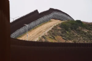 (Concertina wire lines the interior of a border wall separating Tijuana, Mexico, from the United States, June 4, 2025, in San Diego.  AP File Photo: Gregory Bull)