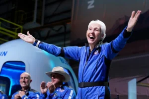 (Wally Funk, right, describes her flight experience as Mark Bezos, left, and Jeff Bezos, left, center, applaud in the spaceport near Van Horn, Texas, July 20, 2021.  AP File Photo: Tony Gutierrez)