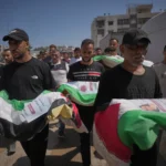 (Mourners carry the flag-draped bodies of Palestinians killed in Israeli strikes during the war with Hamas, whose remains were recently recovered from the rubble, in Gaza City, Thursday, Aug. 20, 2026.  AP Photo: Jehad Alshrafi)