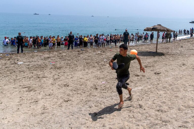 (A migrant runs from Spanish police officers as they cordon off access to the beach for people crossing from Morocco into the Spanish enclave of Ceuta, Friday, July 31, 2026. AP Photo: Antonio Sempere)