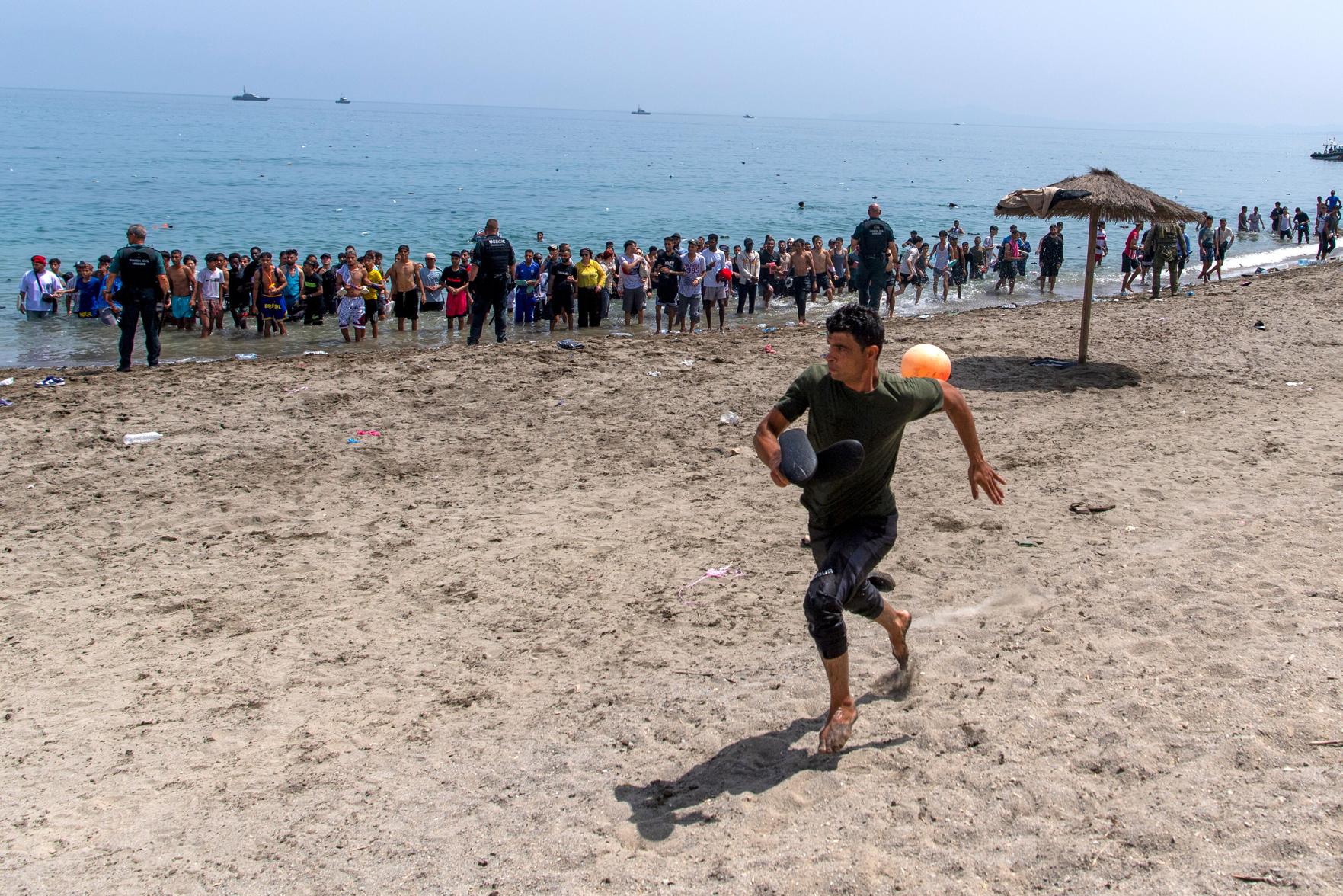 (A migrant runs from Spanish police officers as they cordon off access to the beach for people crossing from Morocco into the Spanish enclave of Ceuta, Friday, July 31, 2026. AP Photo: Antonio Sempere)