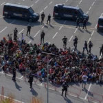 (Migrants who crossed from Morocco into Spain are escorted by Spanish police to temporary shelters after being cleared from a beach in the Spanish exclave of Ceuta on Thursday, Aug. 20, 2026.  AP Photo: Antonio Sempere)