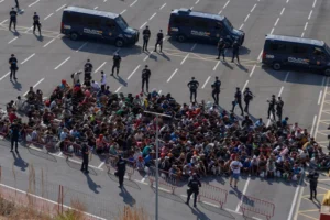 (Migrants who crossed from Morocco into Spain are escorted by Spanish police to temporary shelters after being cleared from a beach in the Spanish exclave of Ceuta on Thursday, Aug. 20, 2026.  AP Photo: Antonio Sempere)