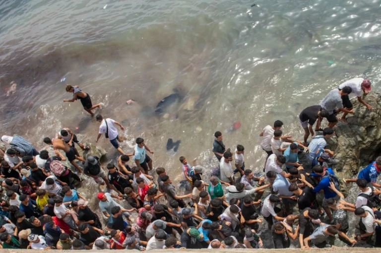 (People walk on a beach as they attempt to cross from the Moroccan northern town of Fnideq to the Spanish enclave of Ceuta, Friday, July 31, 2026.  AP Photo)