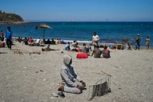 (A migrant who crossed into Spain from Morocco prays on a beach in the Spanish enclave of Ceuta, Sunday, Aug. 2, 2026.  AP Photo: Bernat Armangue)