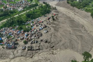 (Damaged houses stand precariously near the swollen, debris-choked banks of the Trishuli River after flash floods in Nepal’s Nuwakot district on Wednesday, Aug. 26, 2026. AP Photo: Niranjan Shrestha)