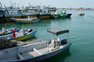 (A man works aboard a boat as a motorboat leaves a harbor in Bandar Abbas, Iran, Sunday, Sept. 6, 2026.  AP Photo: Vahid Salemi)