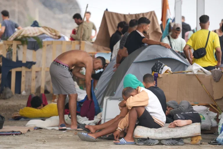 (A migrant sits on a rock at El Trampolín beach in the Spanish exclave of Ceuta, Wednesday, Sept. 2, 2026. AP Photo: Francis González)