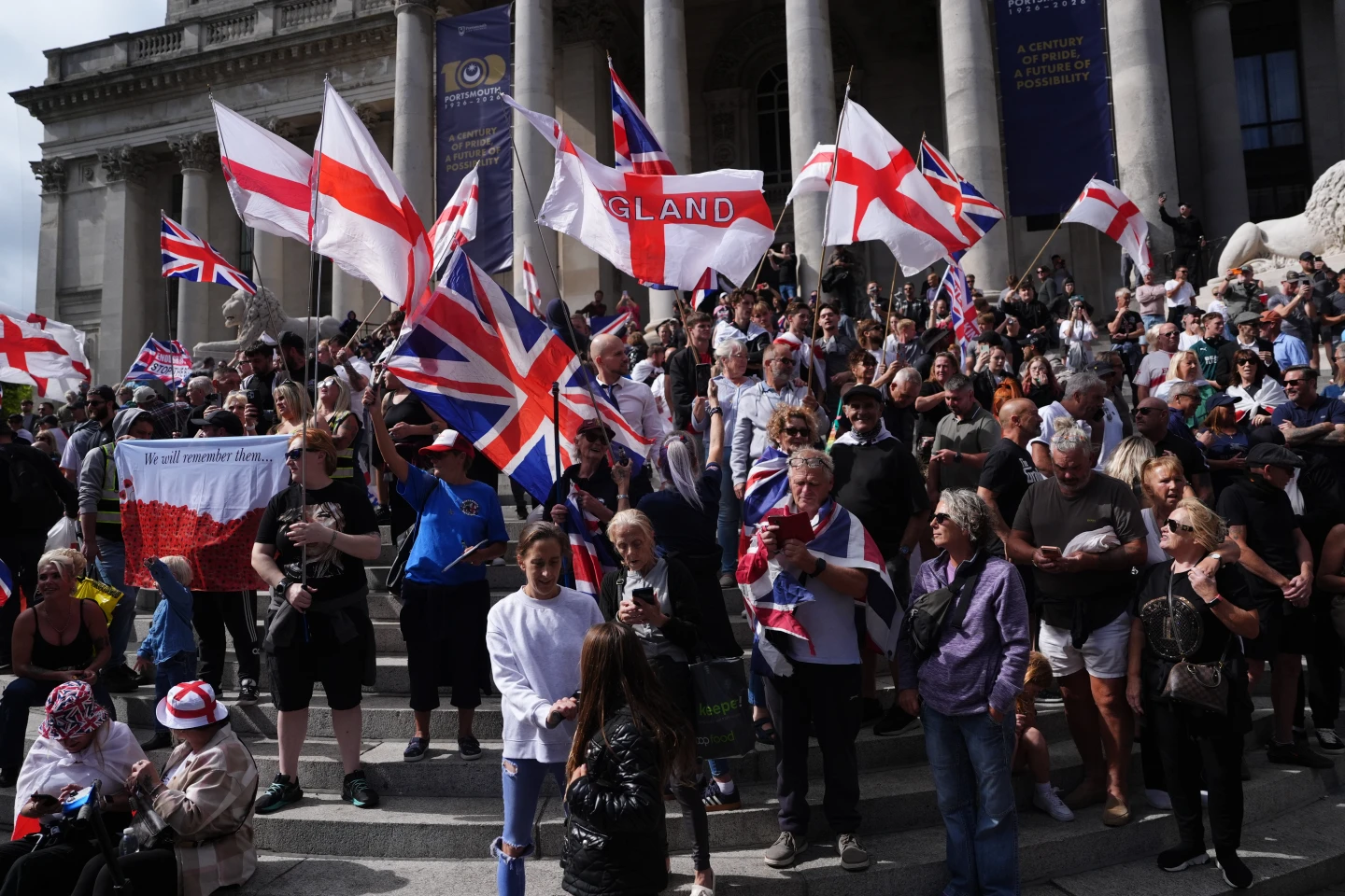(Police standby as people gather outside the Portsmouth Guildhall, Portsmouth, England, to take part in an anti-migrant South Coast Patriots march, Saturday Sept. 12, 2026.  AP Photo: Jonathan Brady PA)