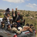 (Yemeni civilians celebrate while riding in the back of a pickup truck in the Bani Matar district, Yemen, Saturday, Sept. 12, 2026, as they follow a convoy carrying Houthi prisoners freed in Mokha on its way to Sanaa following the Houthi takeover of the southern Red Sea port city. Credit: AP-STR)