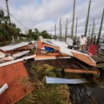 (People retrieve belongings from a collapsed boat house in the aftermath of Hurricane Isaias in Destin, Fla., Saturday, Oct. 10, 2026.  AP Photo: Gerald Herbert)
