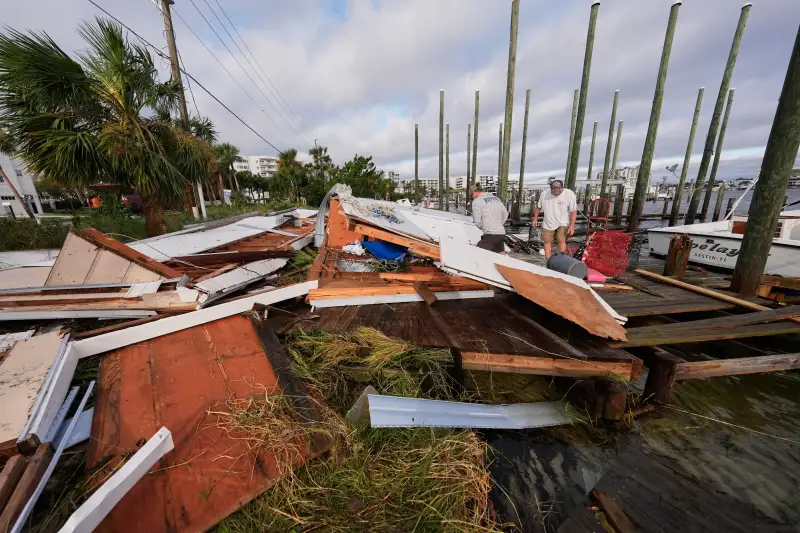 (People retrieve belongings from a collapsed boat house in the aftermath of Hurricane Isaias in Destin, Fla., Saturday, Oct. 10, 2026.  AP Photo: Gerald Herbert)